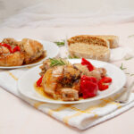 Delicious Italian Chicken Scarpariello with baby red peppers on a plate with bread ont he side.
