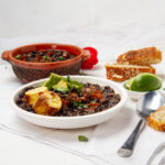 Hearty and satisfying Cuban black bean soup in a owl with fresh avocado garnish.