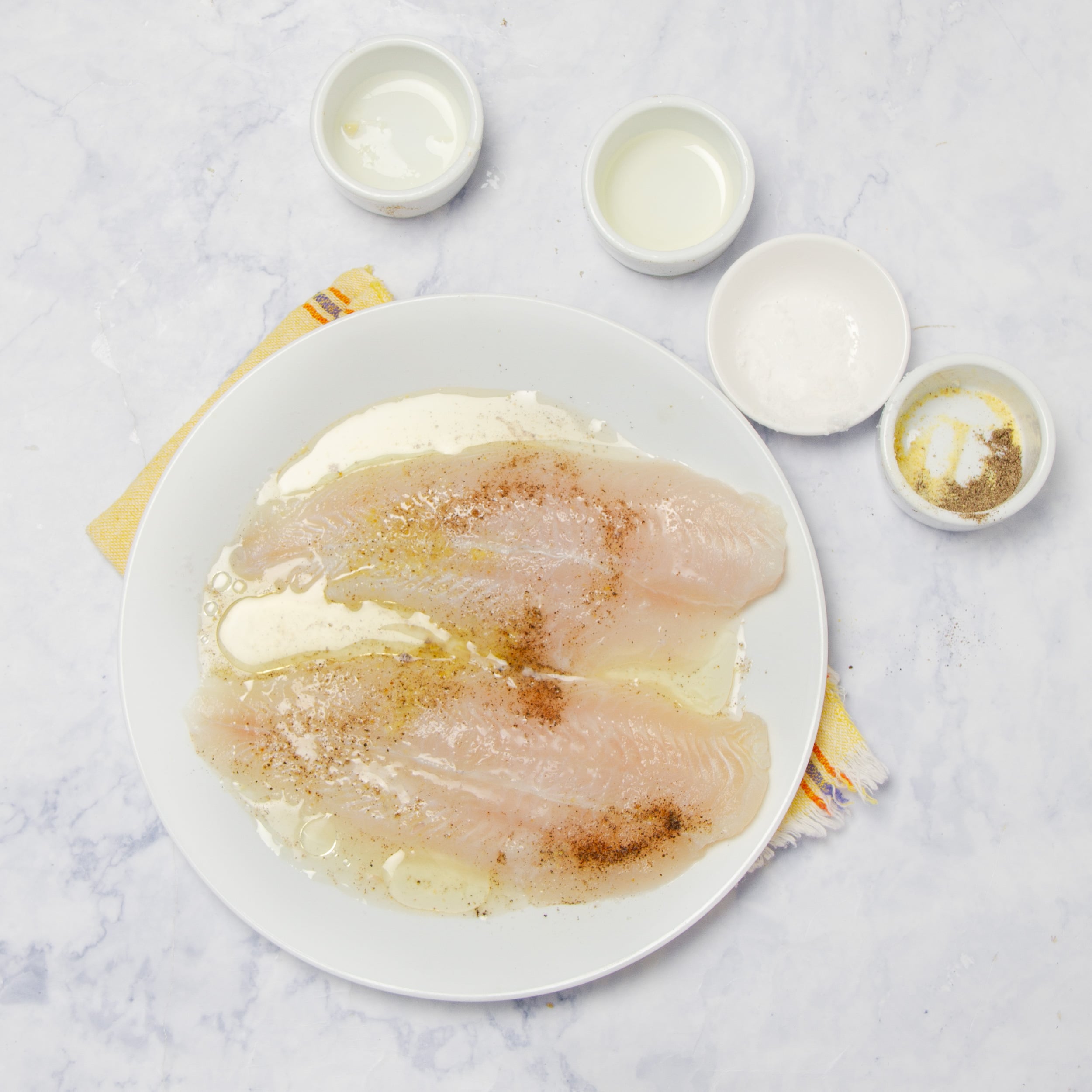 Fish marinating in seasonings on a plate. 