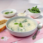 Creamy Italian Stracciatella Soup in a bowl with fresh basil and parmesan on the side.