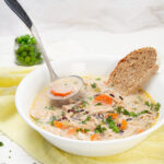 Creamy and nourishing Wild Rice Chicken Soup in a bowl with a piece of bread.