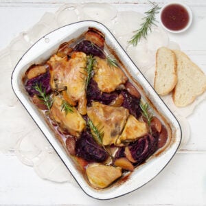 Easy yet satisfying Apple Cider Baked Chicken and Cabbage in a baking dish with bread on the side.