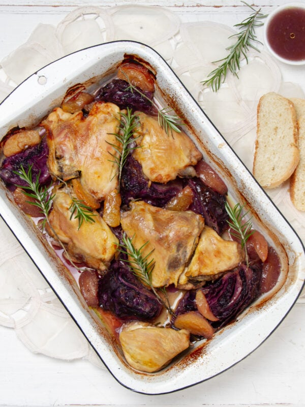 Easy yet satisfying Apple Cider Baked Chicken and Cabbage in a baking dish with bread on the side.
