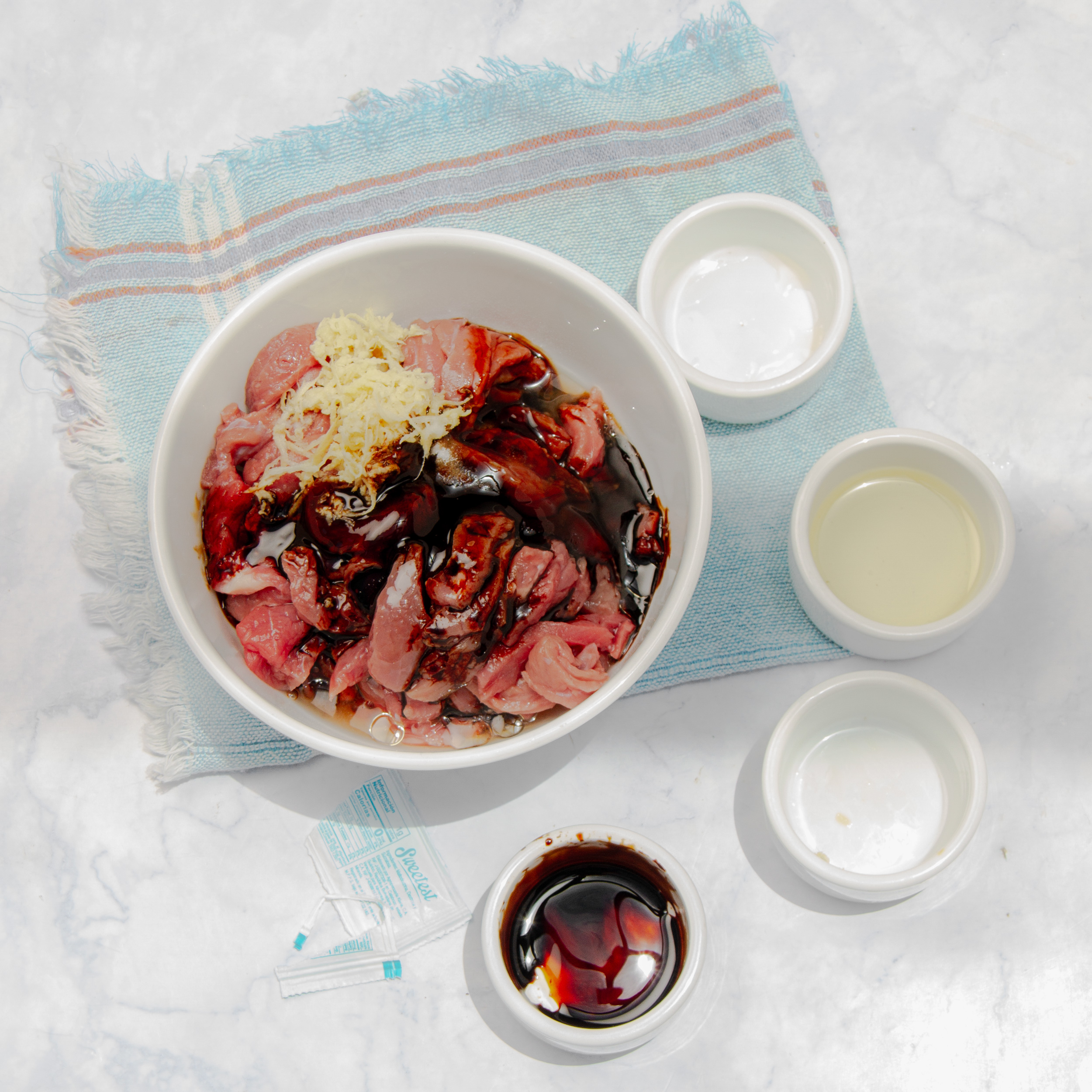 Beef slices marinating in a small bowl.
