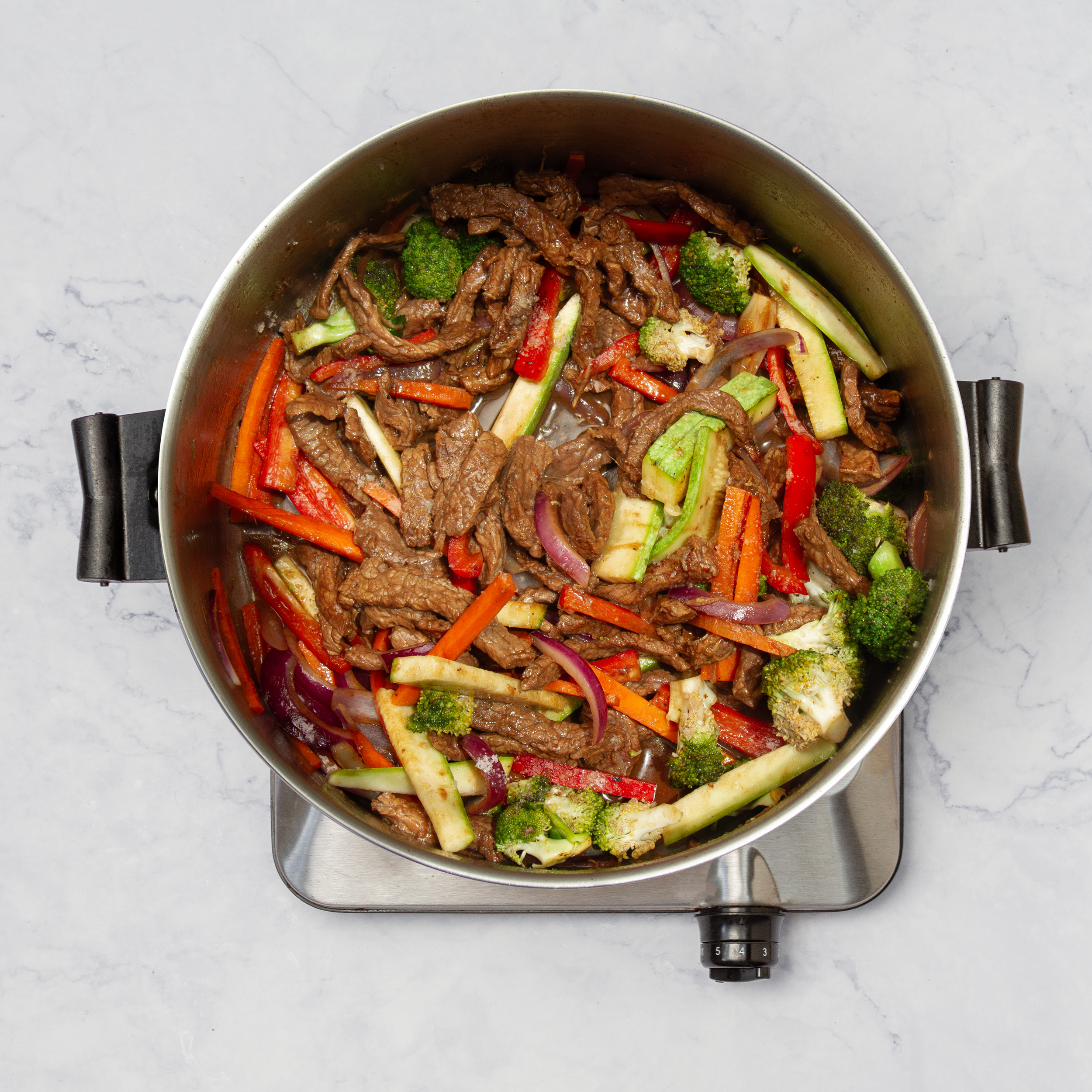 Stir-fried beef and veggies combined in the pan with sauce ingredients.