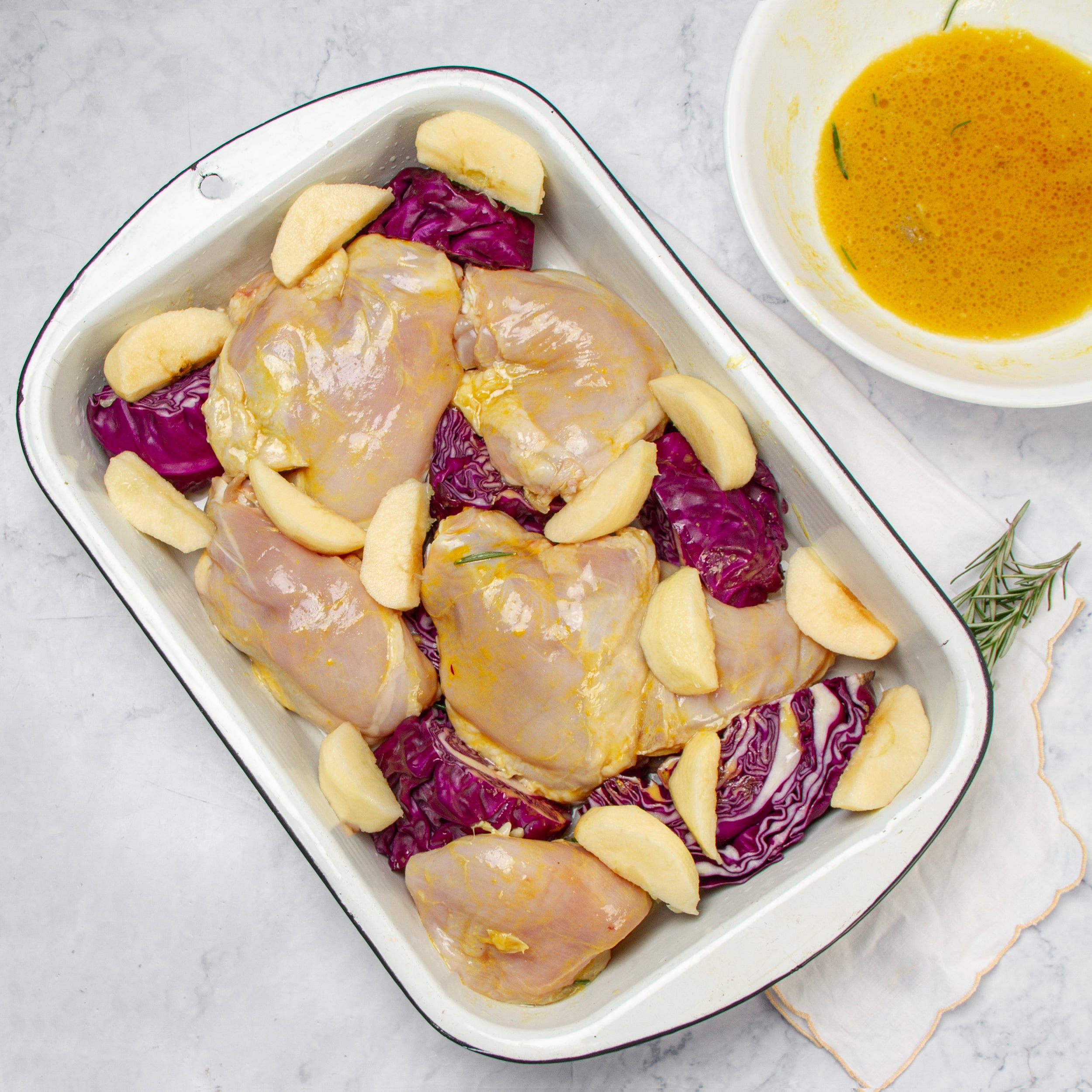 Apple slices added to the chicken and cabbage in the baking dish. 