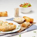 Crunchy and delicious Buffalo Chicken Egg Rolls on a plate with a salad on the side.