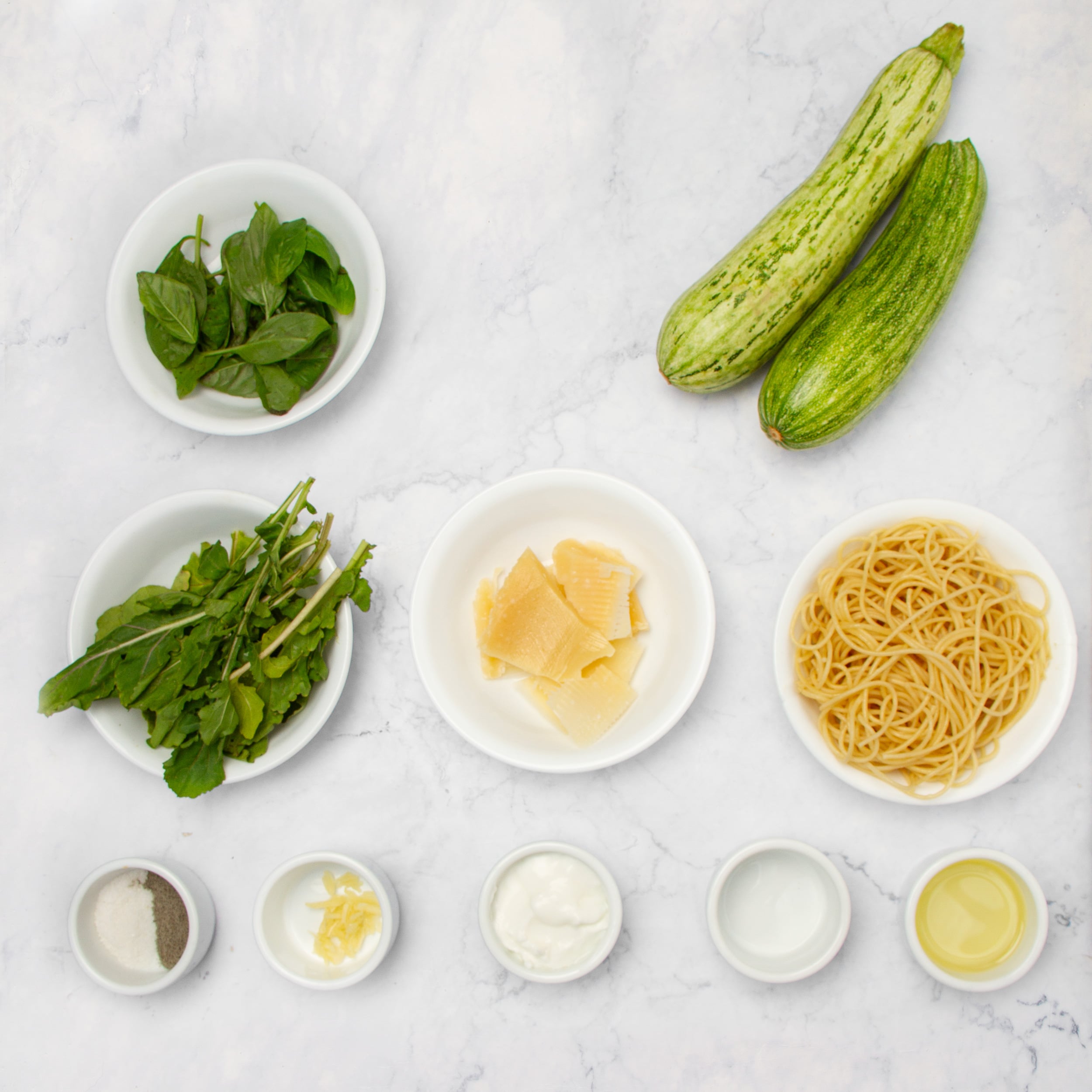 Pesto Pasta ingredients in separate dishes on a countertop.