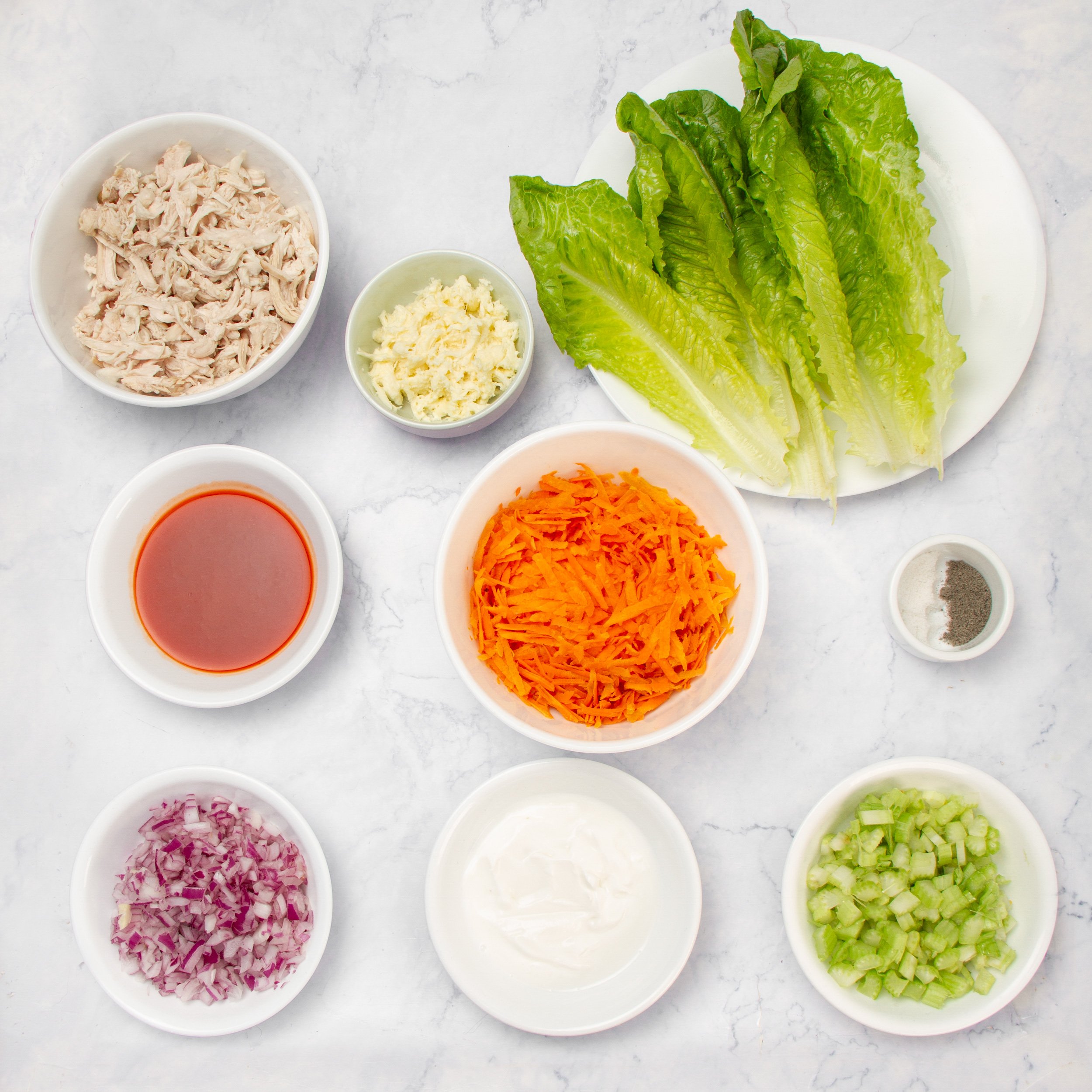 Buffalo Chicken Salad ingredients in separate dishes on a countertop.