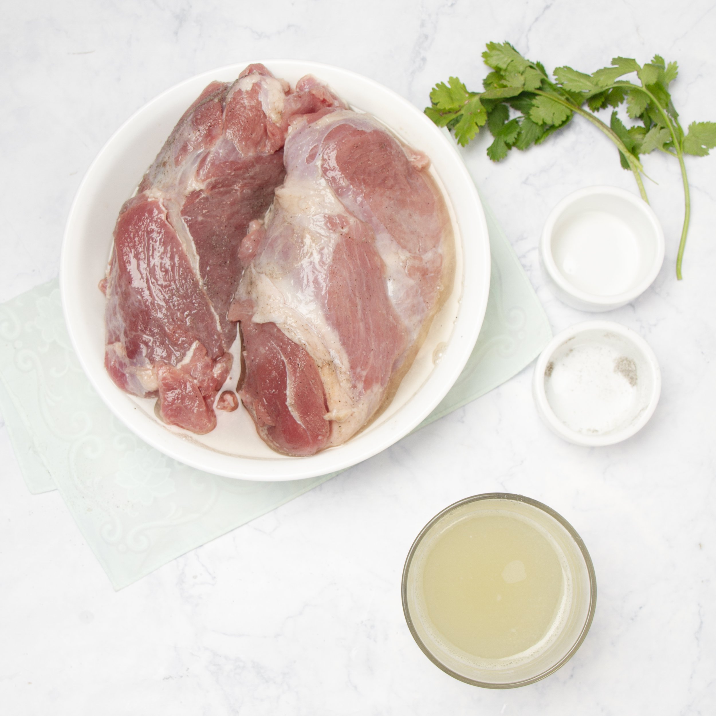 Raw pork tenderloins with pineapple marinade in a shallow dish.