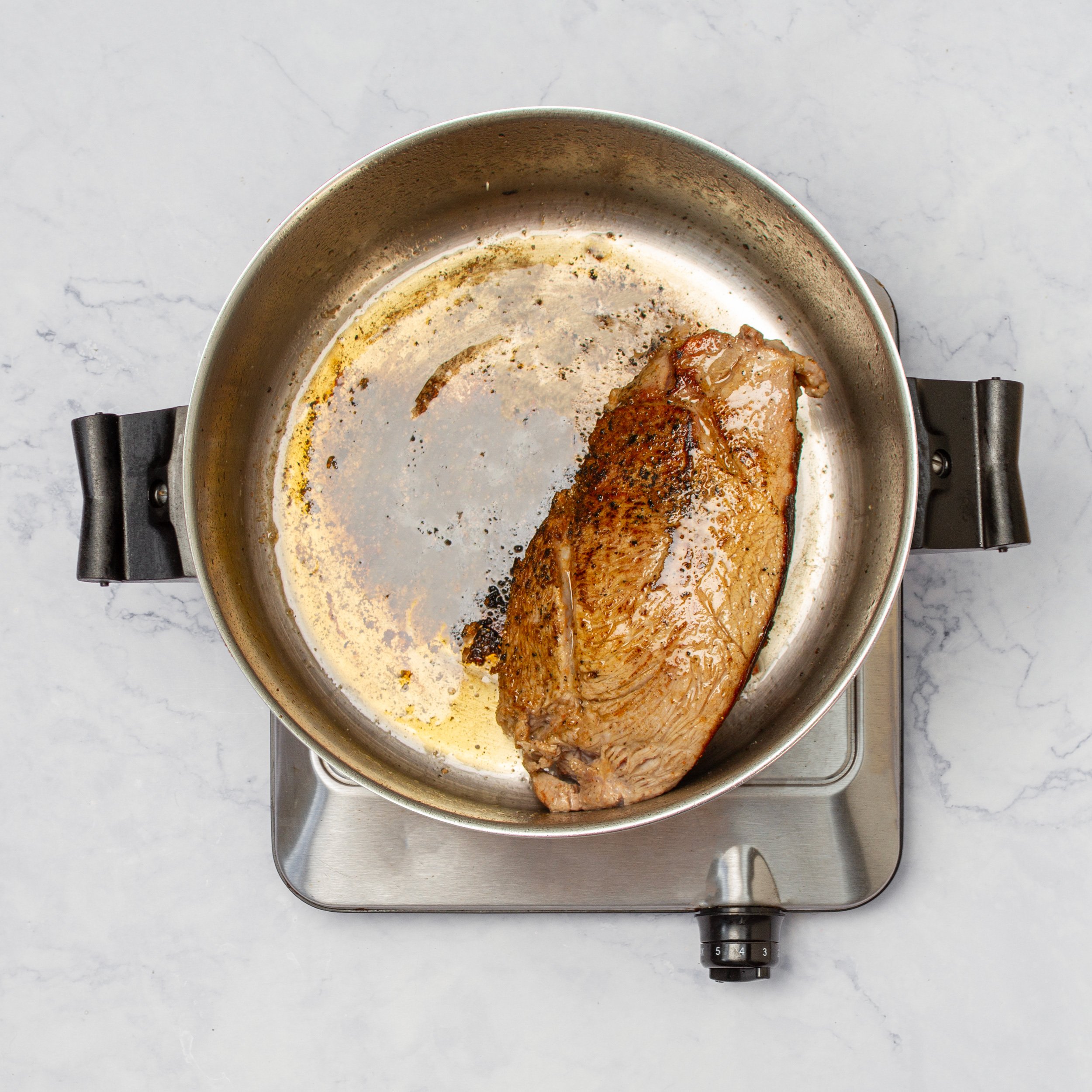 Marinated pork tenderloin cooking in a pan.