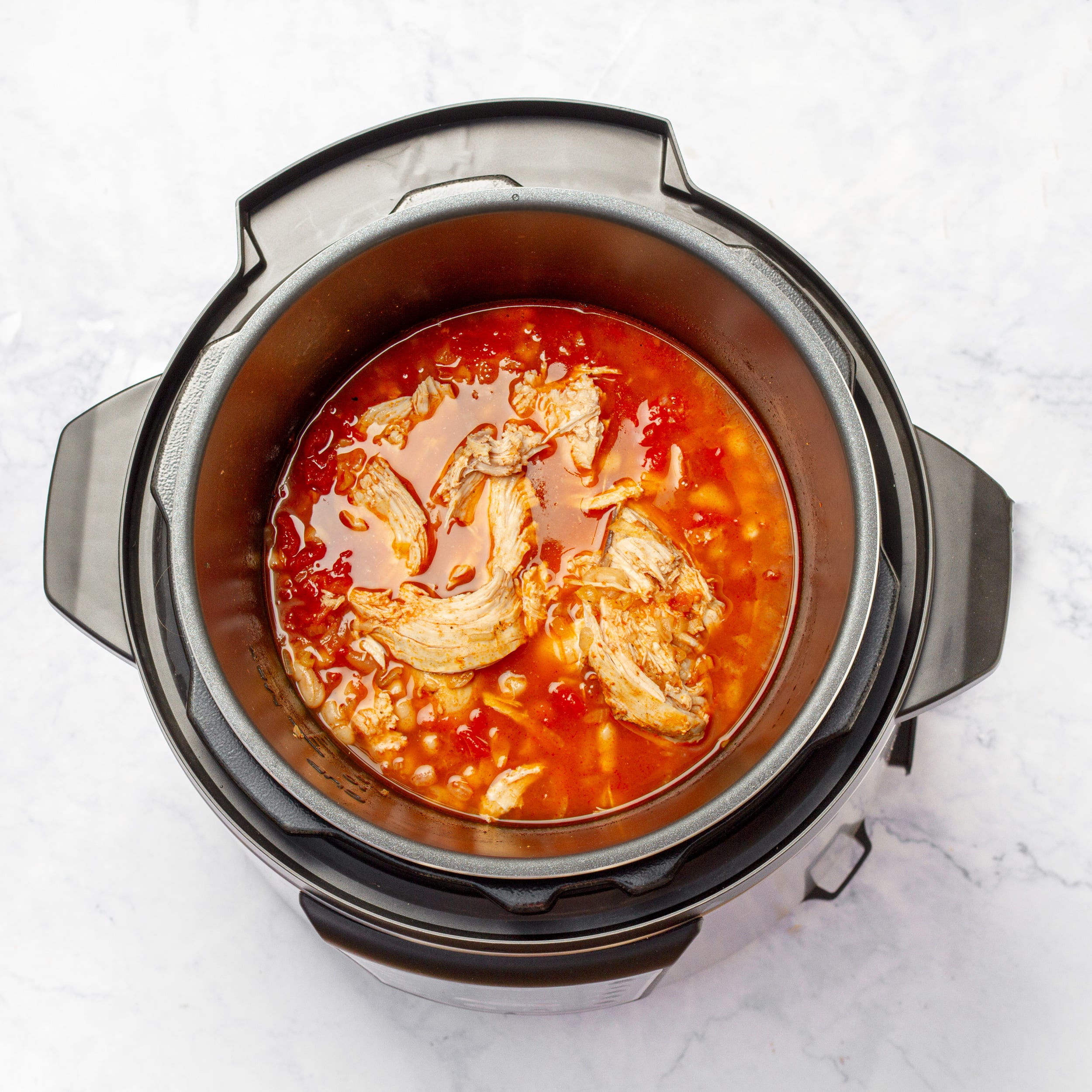 Once the chili has cooked, shred the chicken breast. 