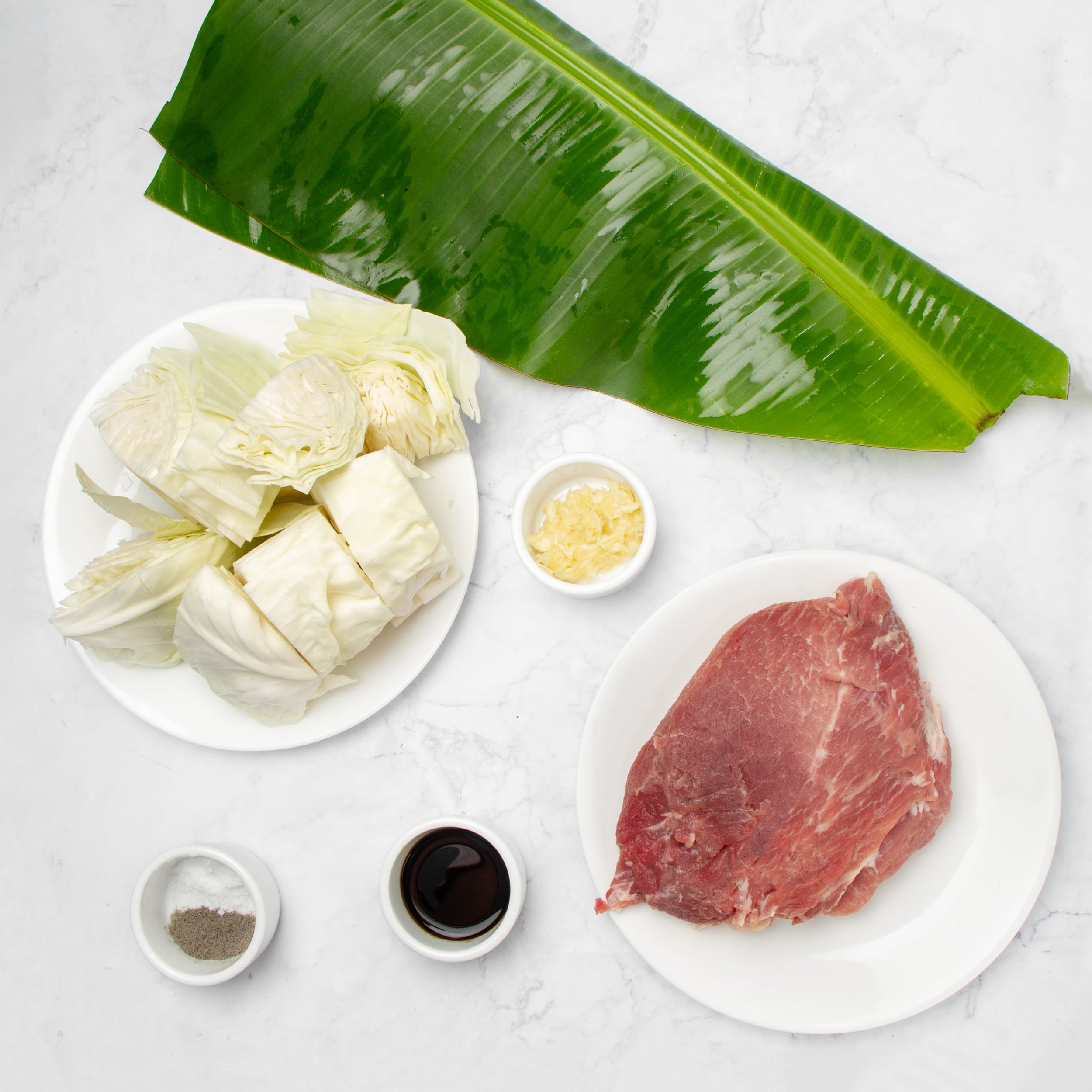 Few, simple Kalua Pork ingredients in separate dishes on a countertop. 