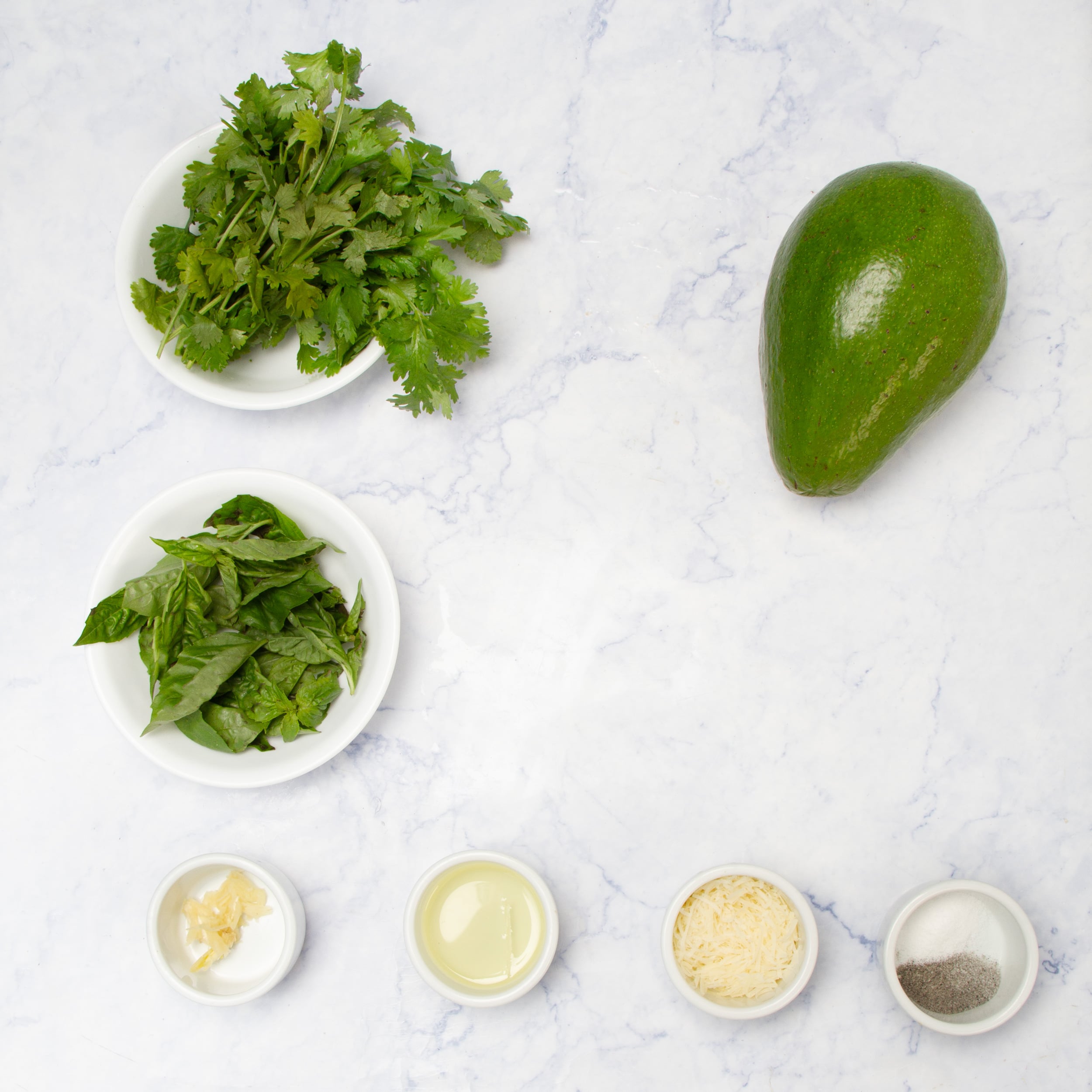 Simple and fresh Healthy Pesto ingredients in separate dishes on a counter.