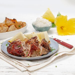 Tender, tropical Kalua Pork on a plate with braised cabbage on the side—easy and delicious!