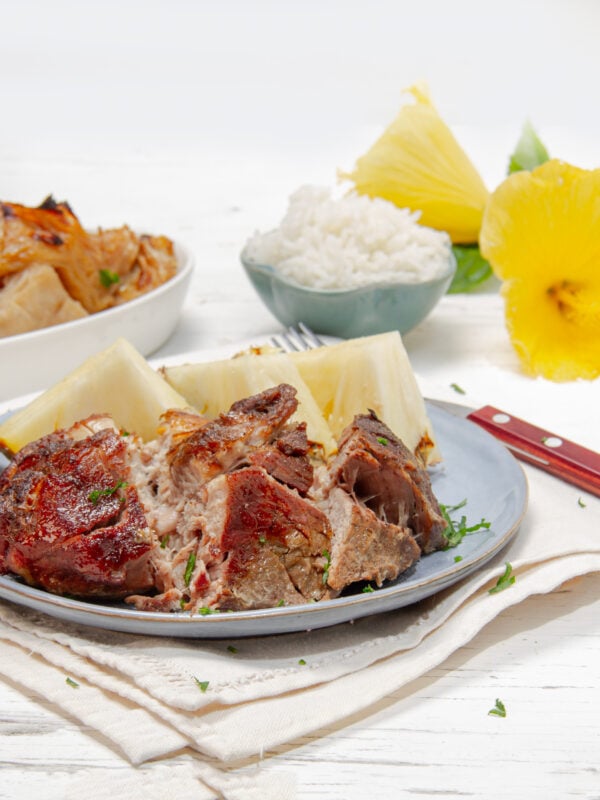 Tender, tropical Kalua Pork on a plate with braised cabbage on the side—easy and delicious!