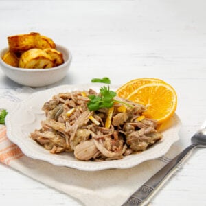 Tender, juicy, and full of flavor! Mojo Cuban Pork shredded on a plate with orange slices.