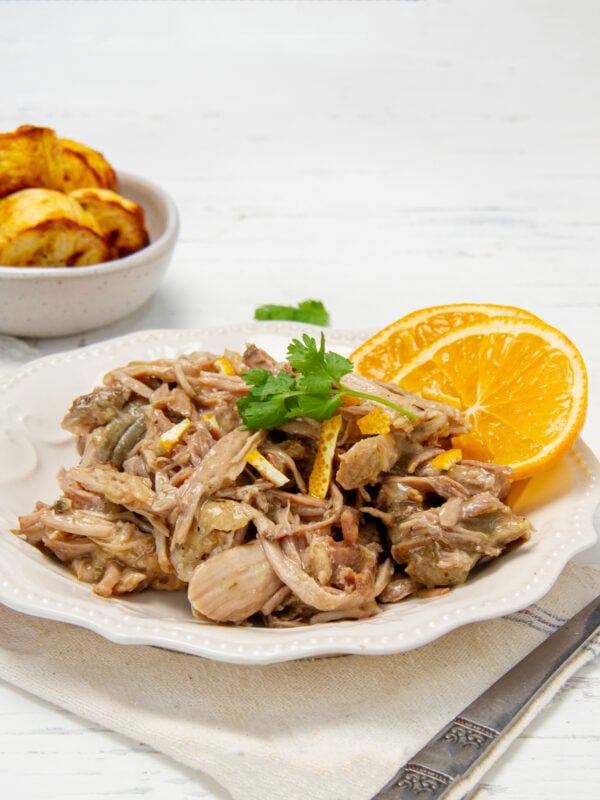 Tender, juicy, and full of flavor! Mojo Cuban Pork shredded on a plate with orange slices.