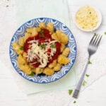 Soft and flavorful pumpkin gnocchi with sauce and cheese in a bowl.