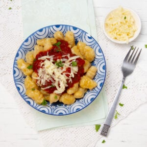 Soft and flavorful pumpkin gnocchi with sauce and cheese in a bowl.