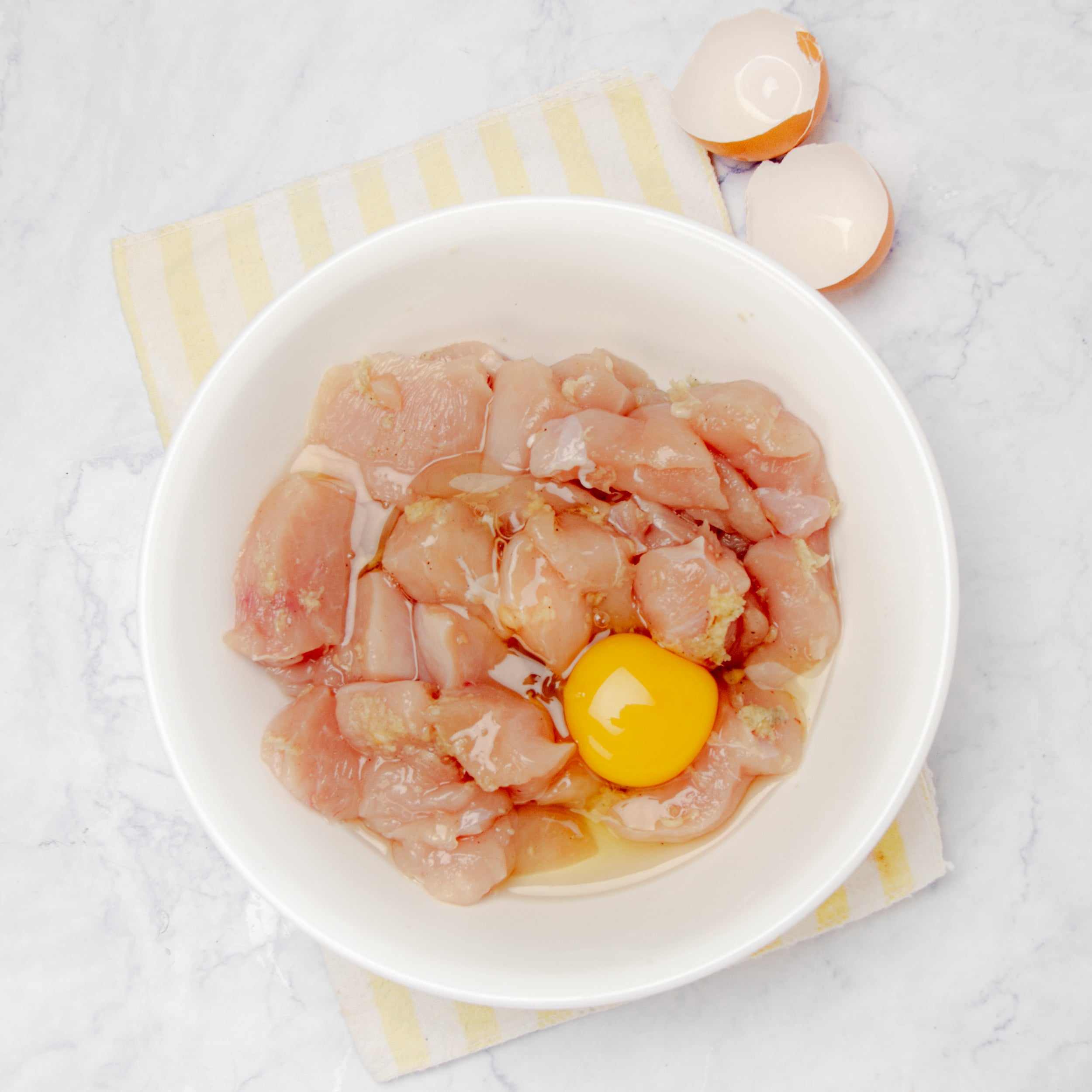 Chopped, raw chicken with seasonings and an egg in a small bowl. 