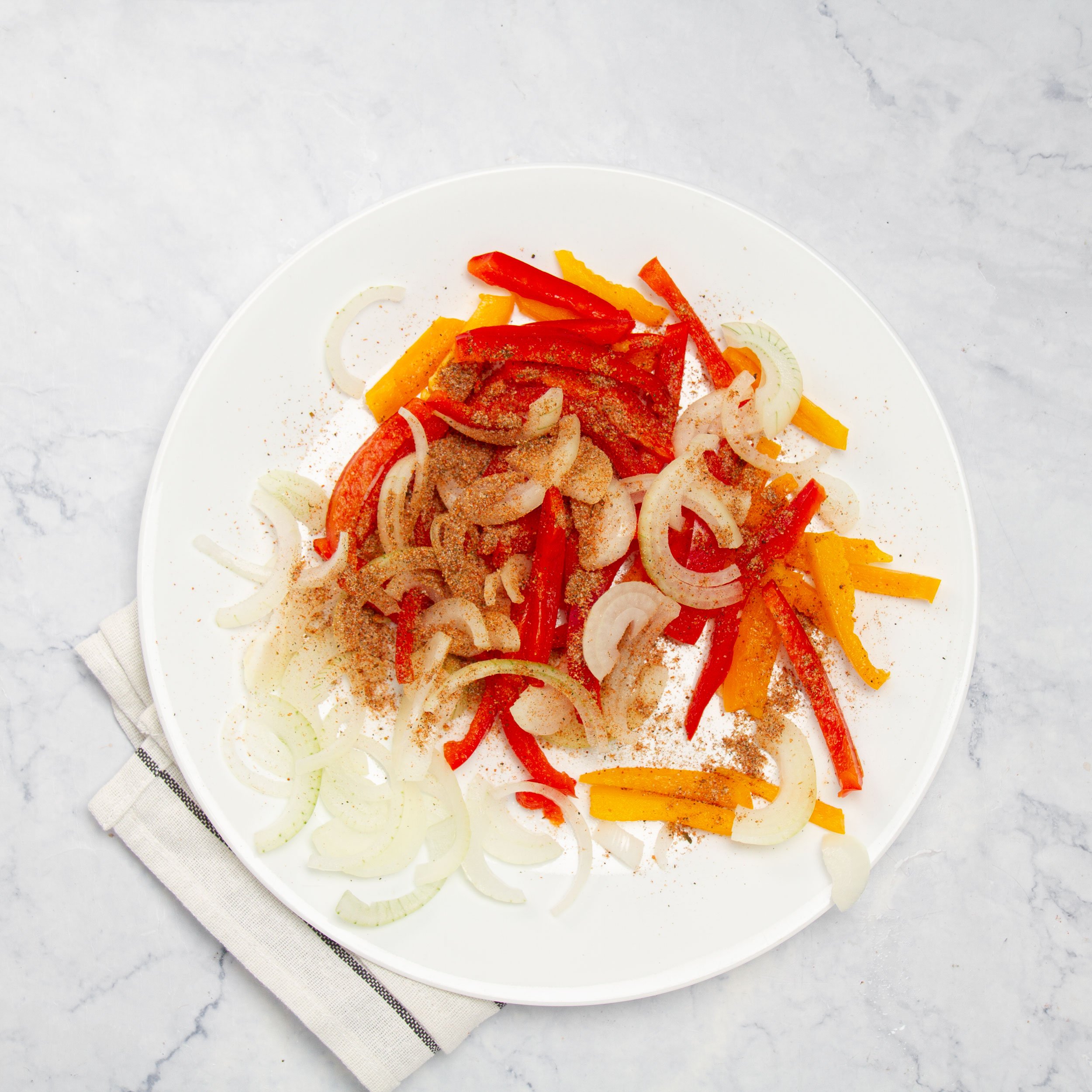 Sliced onions and peppers on a small plate. 