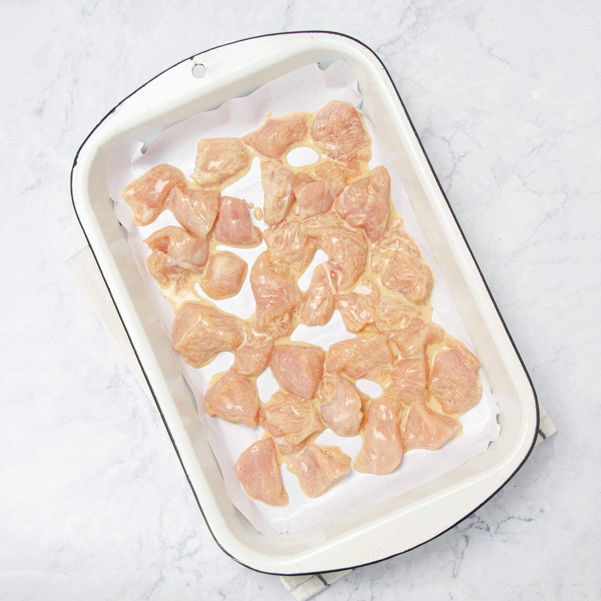 Chicken bites breaded and laid out in a baking dish.