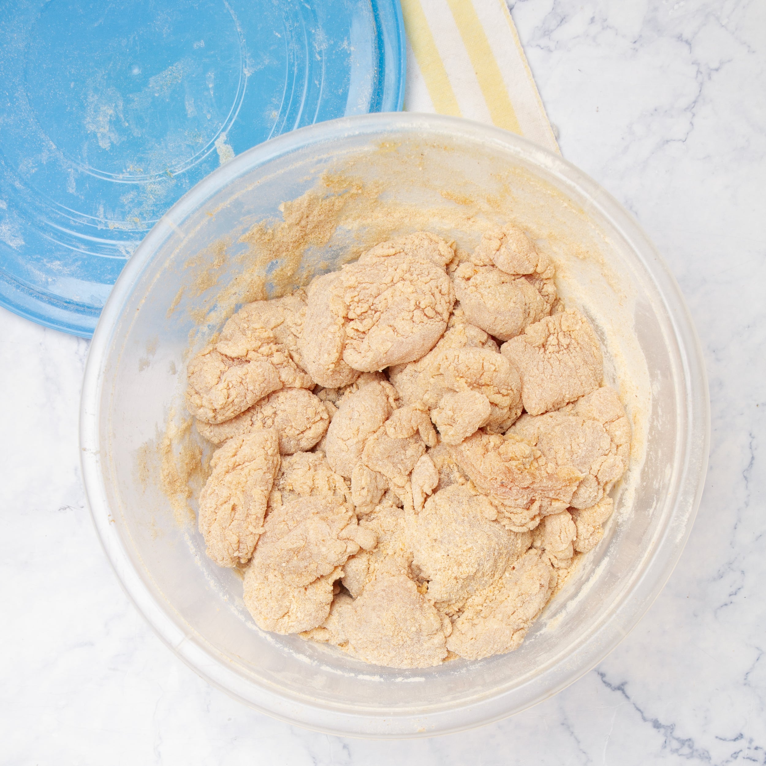 An way way to bread your chicken all at once: flour added to the egg-coated chicken in a bowl. 