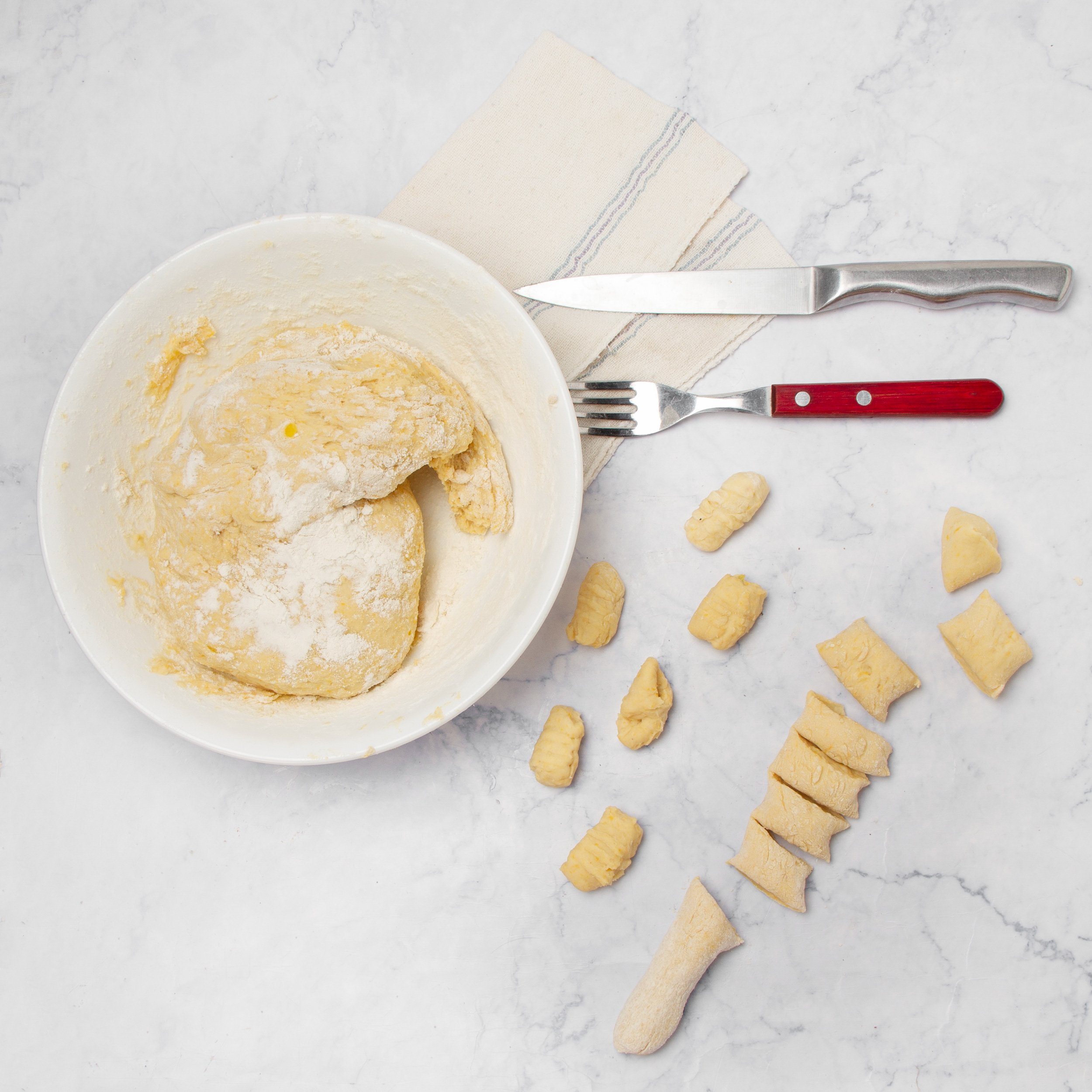 Dough cut into small gnocchi pieces on a countertop.
