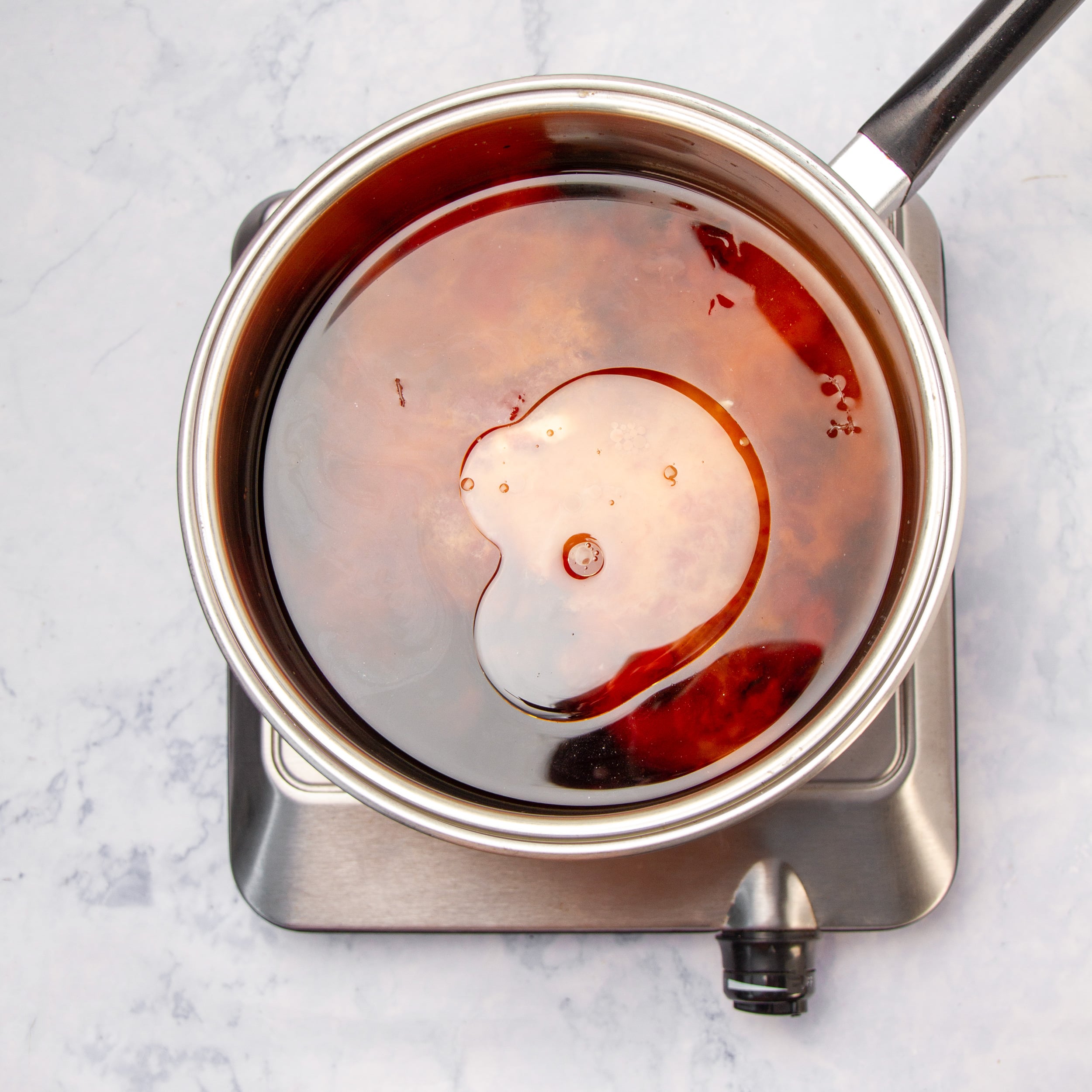 Bold and savory sauce ingredients cooking in a small saucepan. 