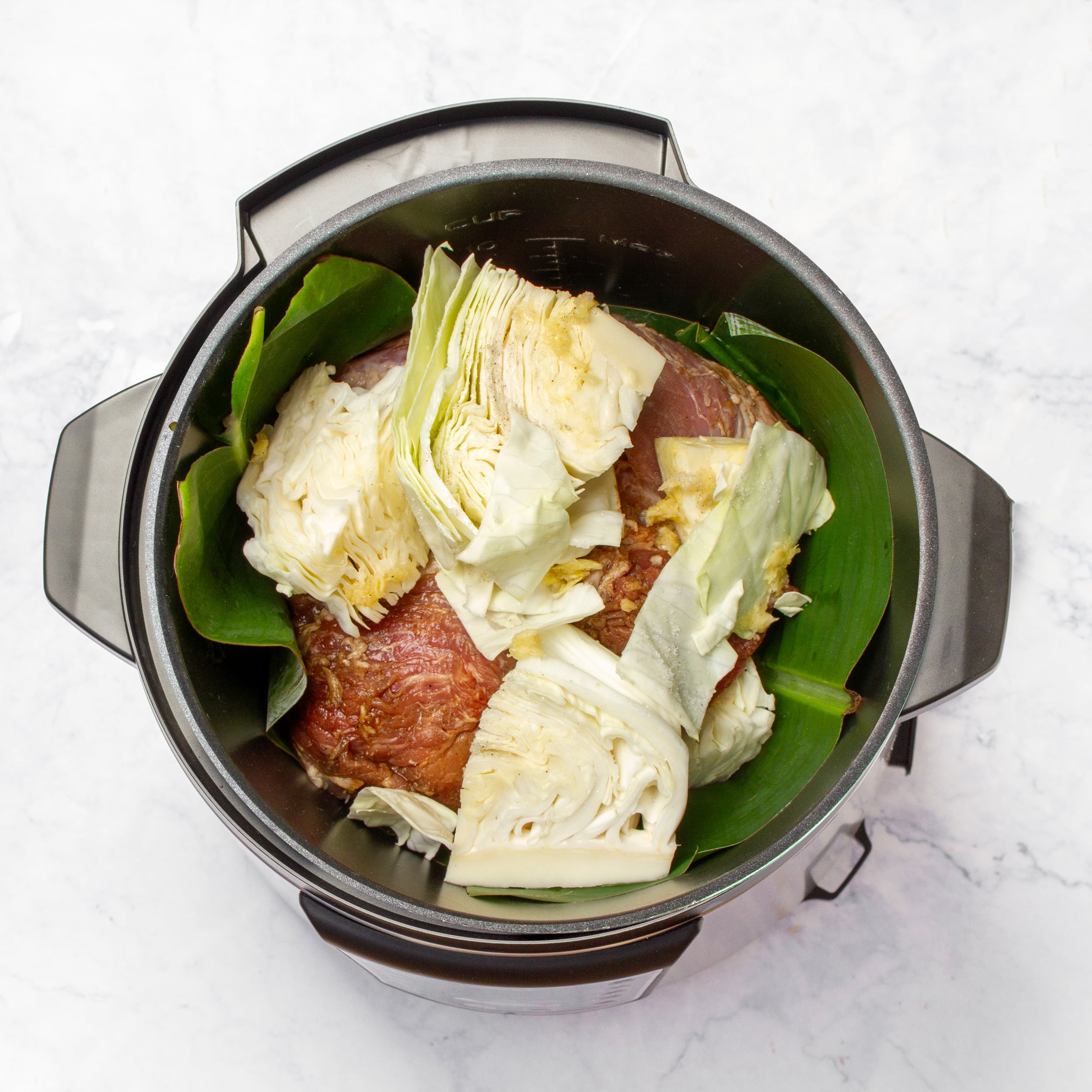 Remaining cabbage leaves added on top of the pork shoulder in the slow cooker. 