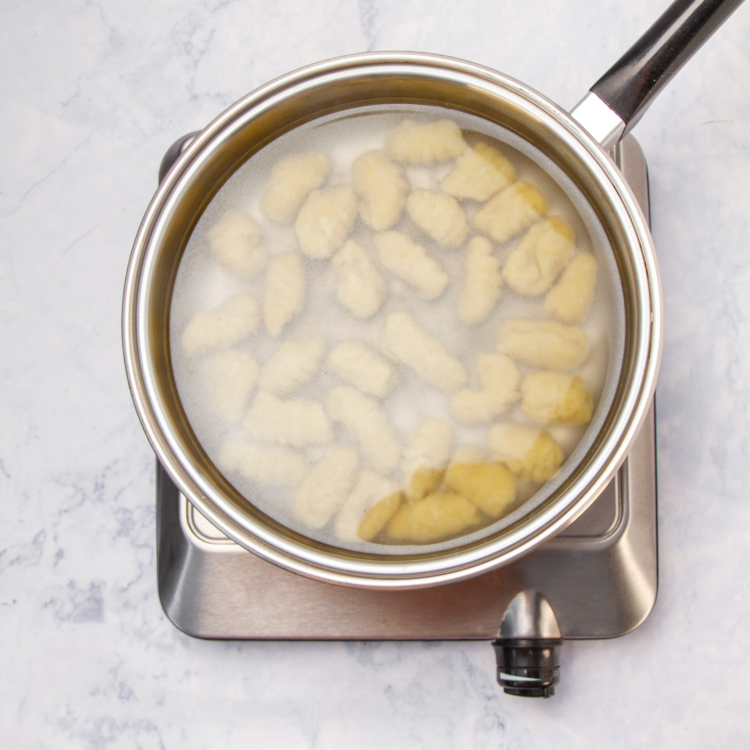 Gnocchi pieces boiling in a pot of water.