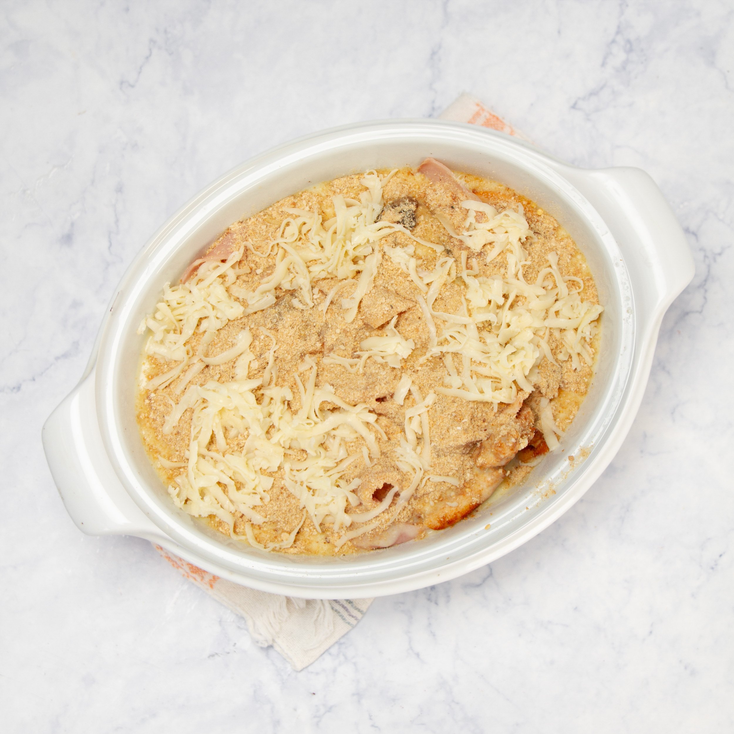 Creamy sauce and breadcrumbs added to the cooked meats in the casserole dish.