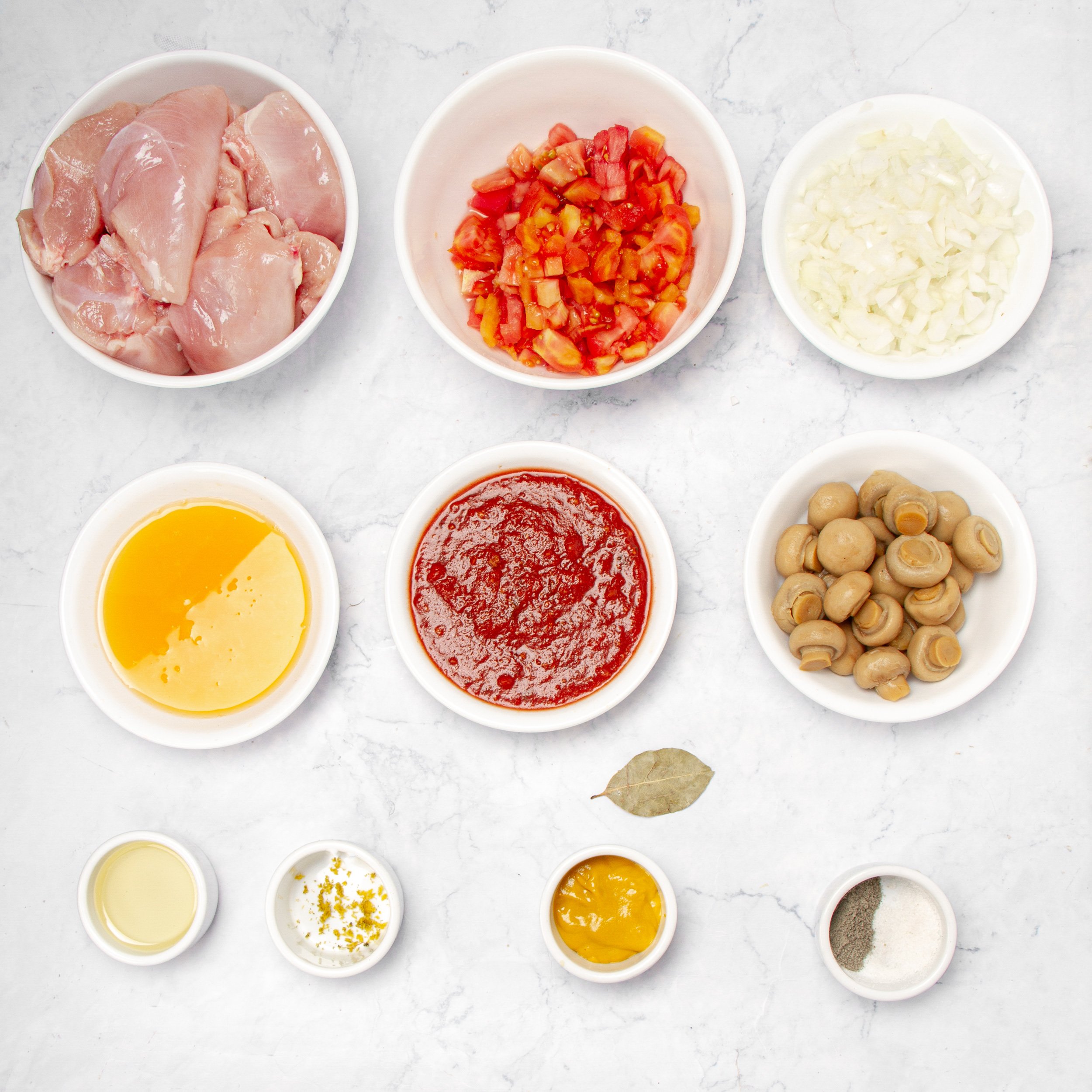 Fresh and vibrant Chicken Marengo ingredients in separate dishes.