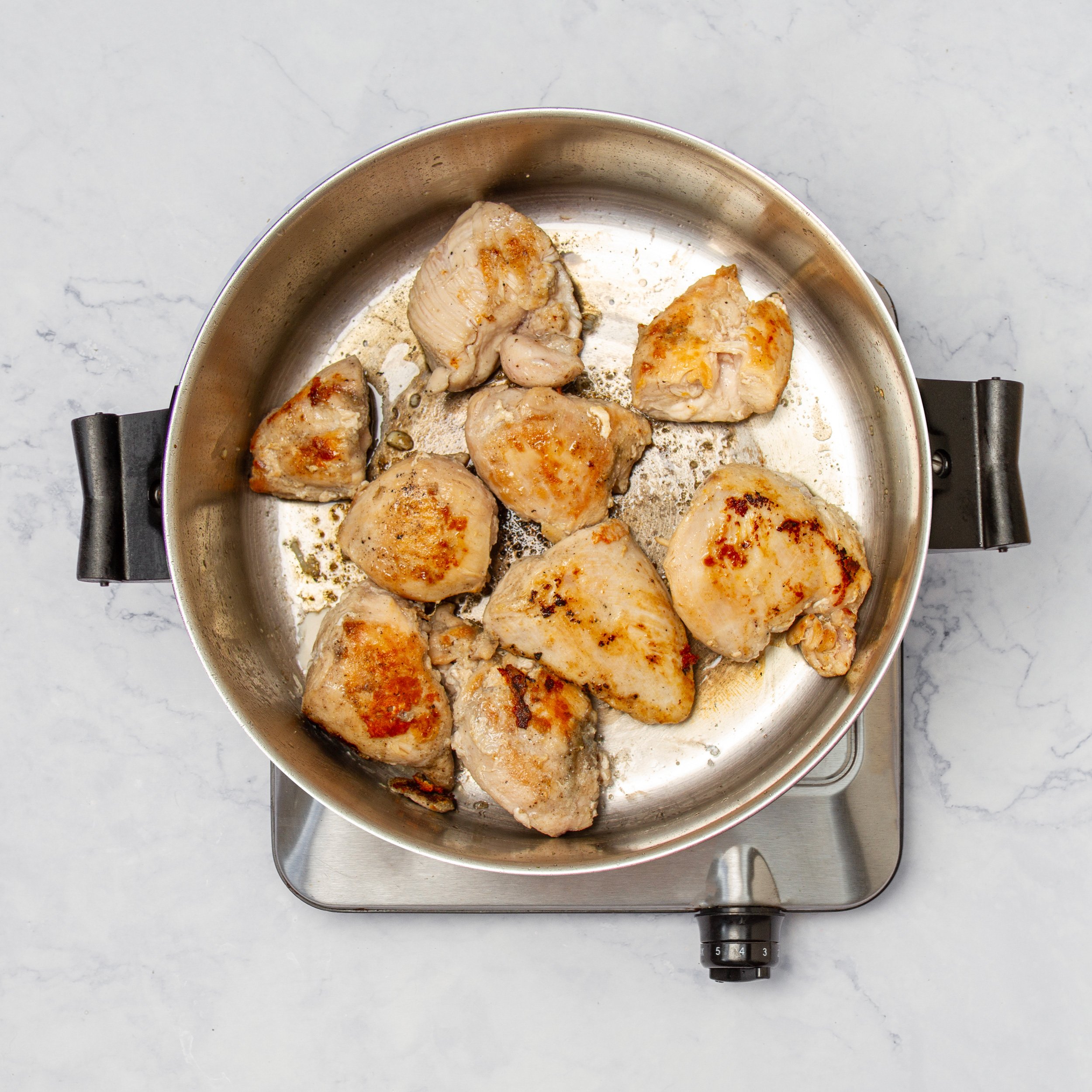 Seasoned chicken cooking in a hot pan.