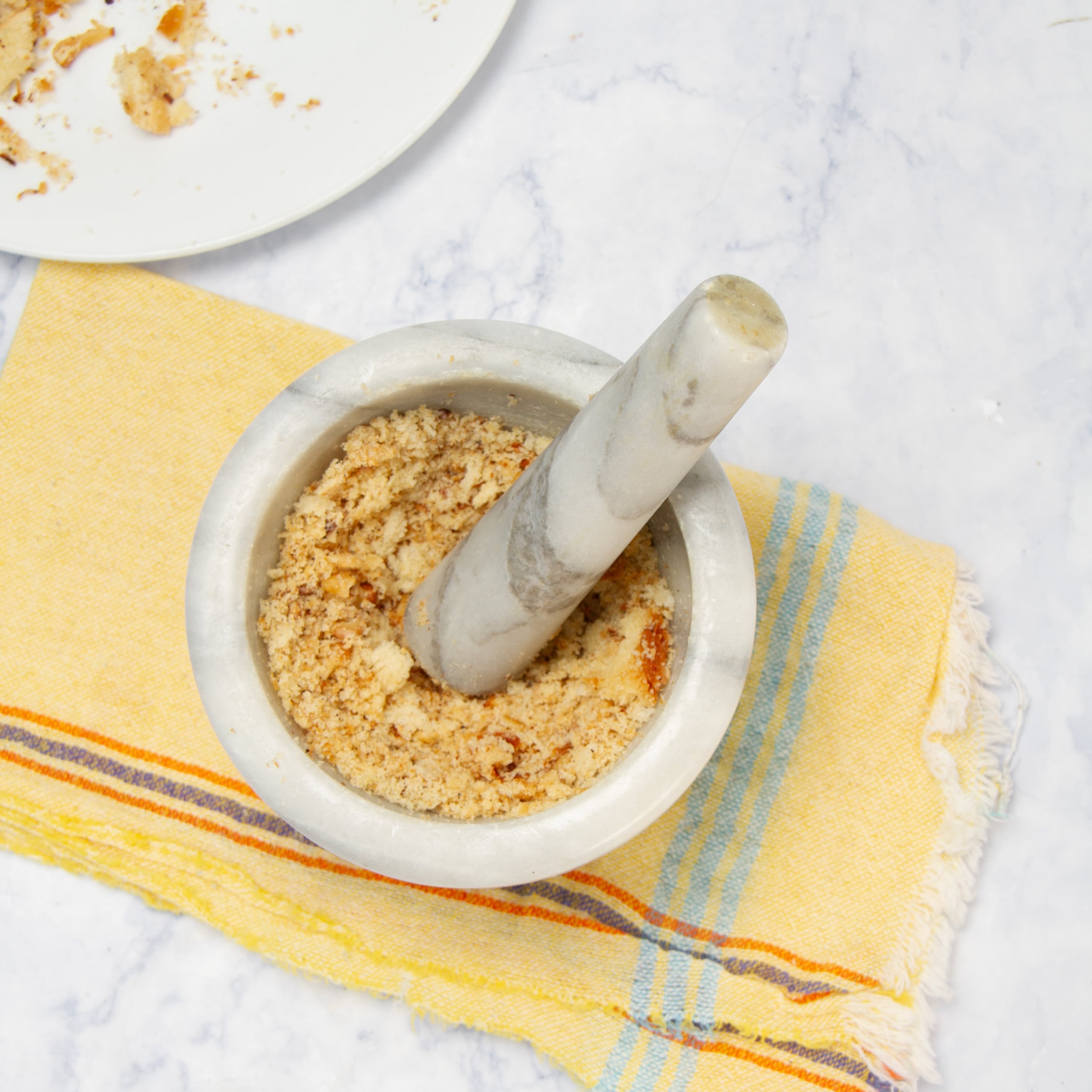 Toasted bread and nuts being crushed in a mortar. This is used to thicken the sauce. 
