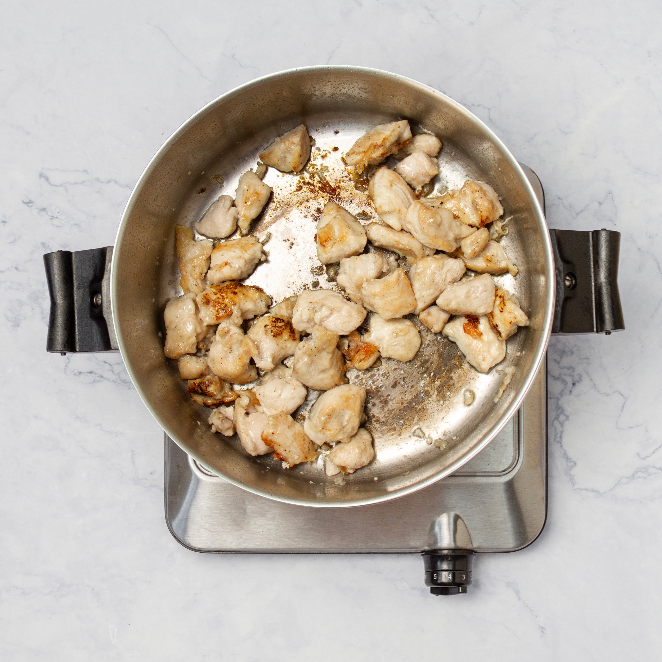 Seasoned chicken cooking in a hot skillet. 