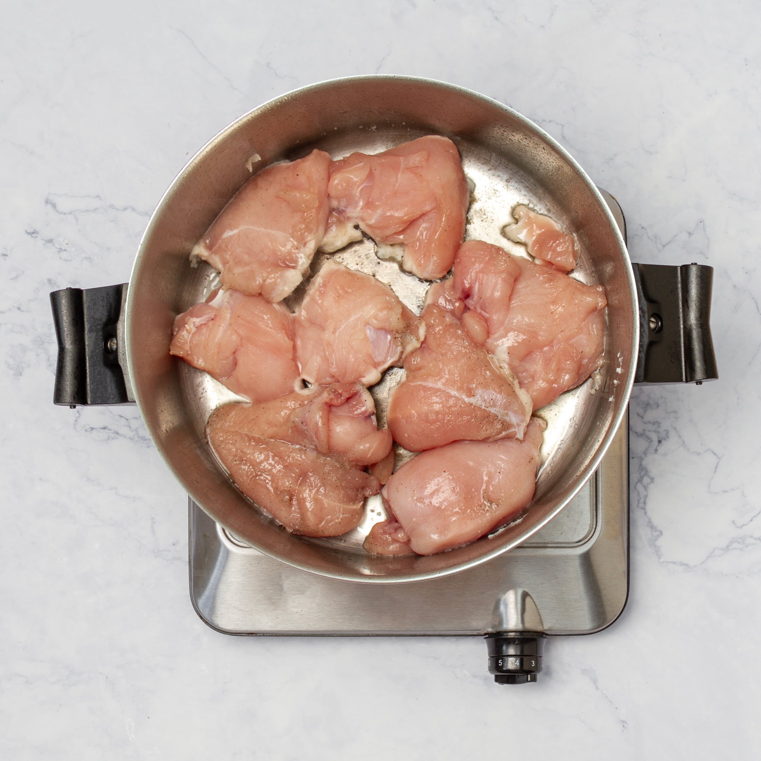 Seasoned chicken cooking in a hot pan. 