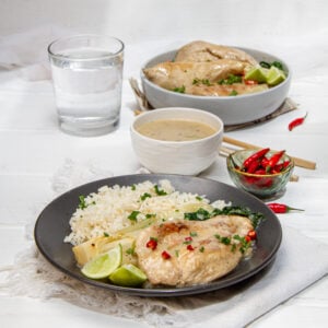 Zesty Thai-inspired Coconut Lime Chicken on a plate with rice, bok choy, and extra sauce on the side.