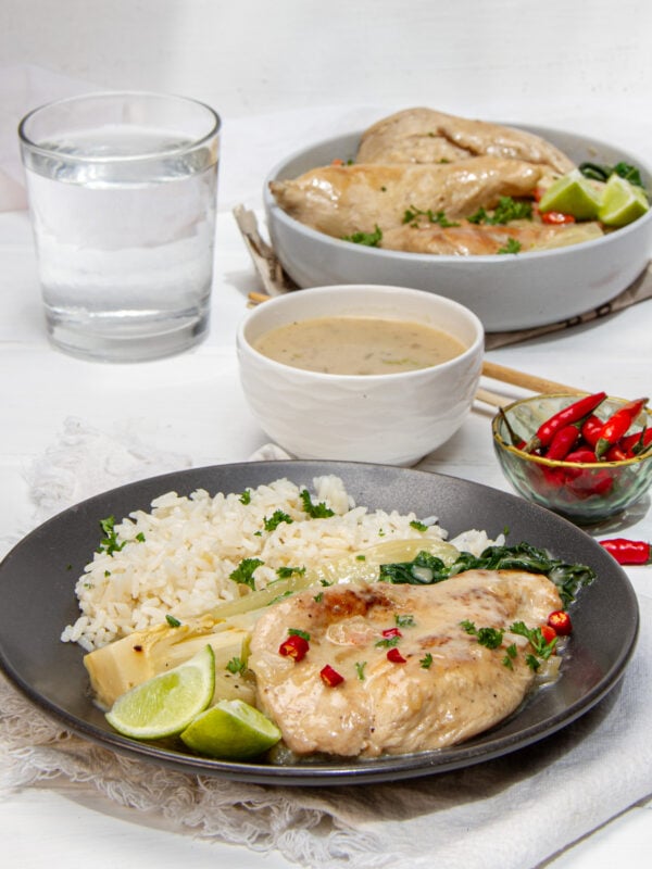 Zesty Thai-inspired Coconut Lime Chicken on a plate with rice, bok choy, and extra sauce on the side.