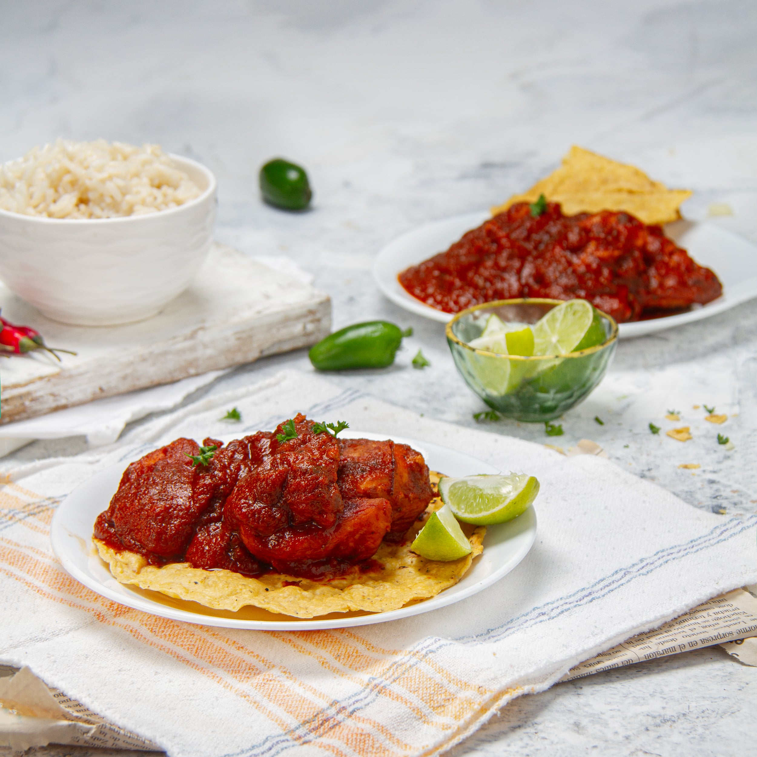 Saucy with deep flavor&mdash;Mexican Chicken Adobo on a plate with a corn tortilla and fresh lime wedges on the side.