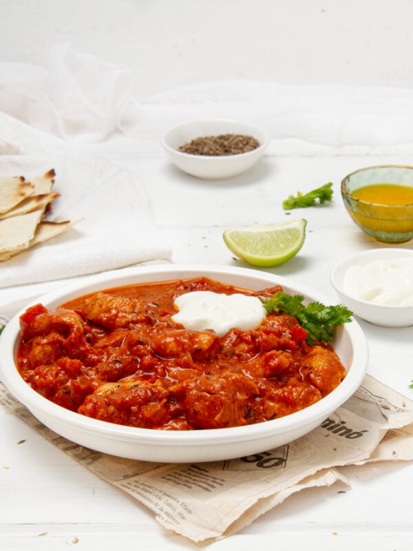Rich and flavorful Chicken Rogan Josh with a dollop of yogurt in a dish.