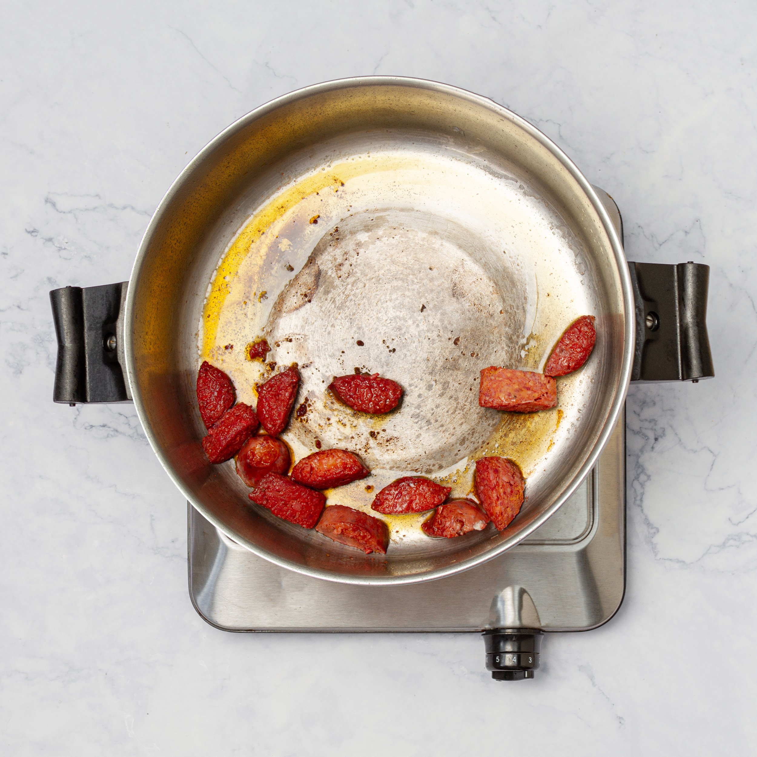Sausage slices pan-frying on a stove.