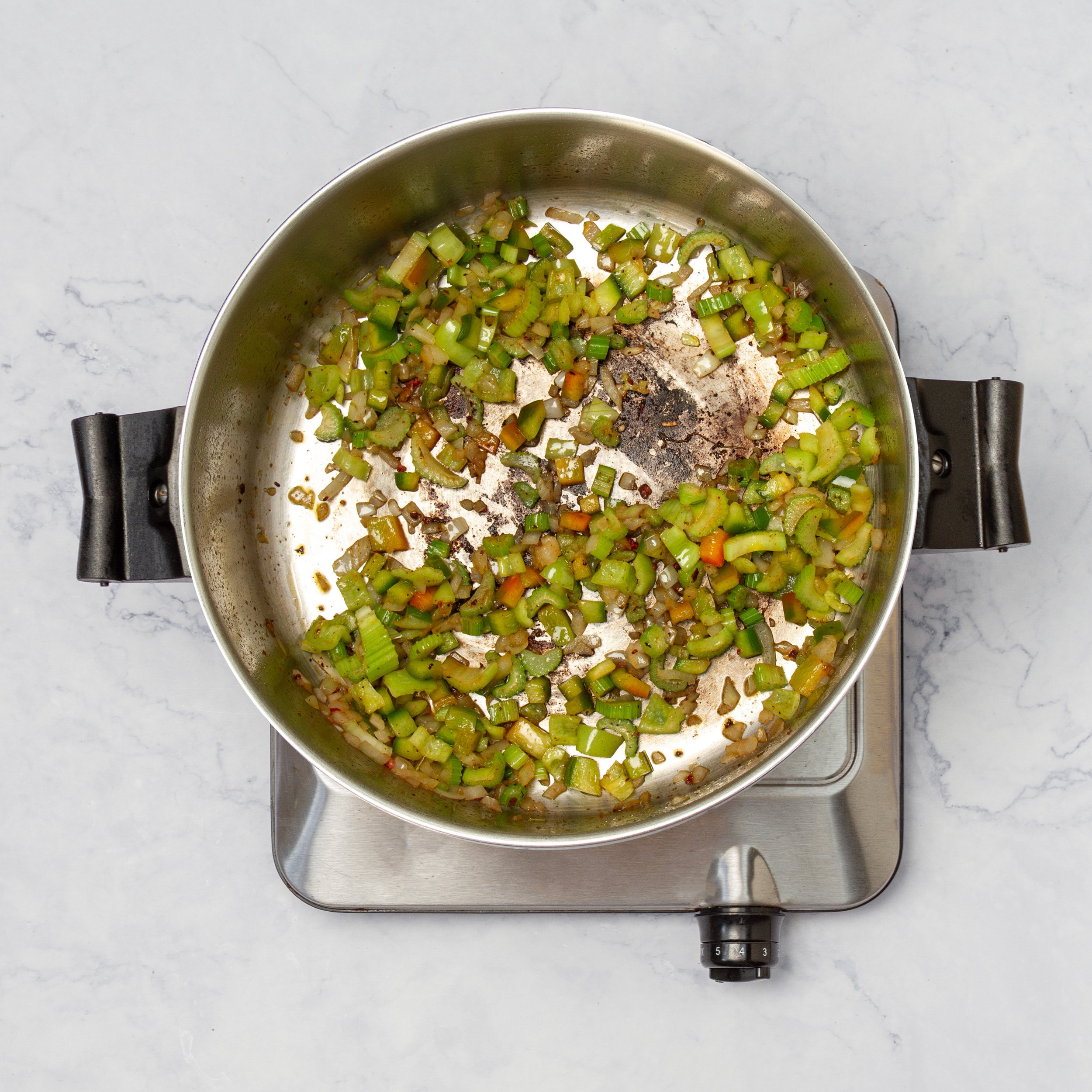 Aromatics and spices cooking in a skillet.