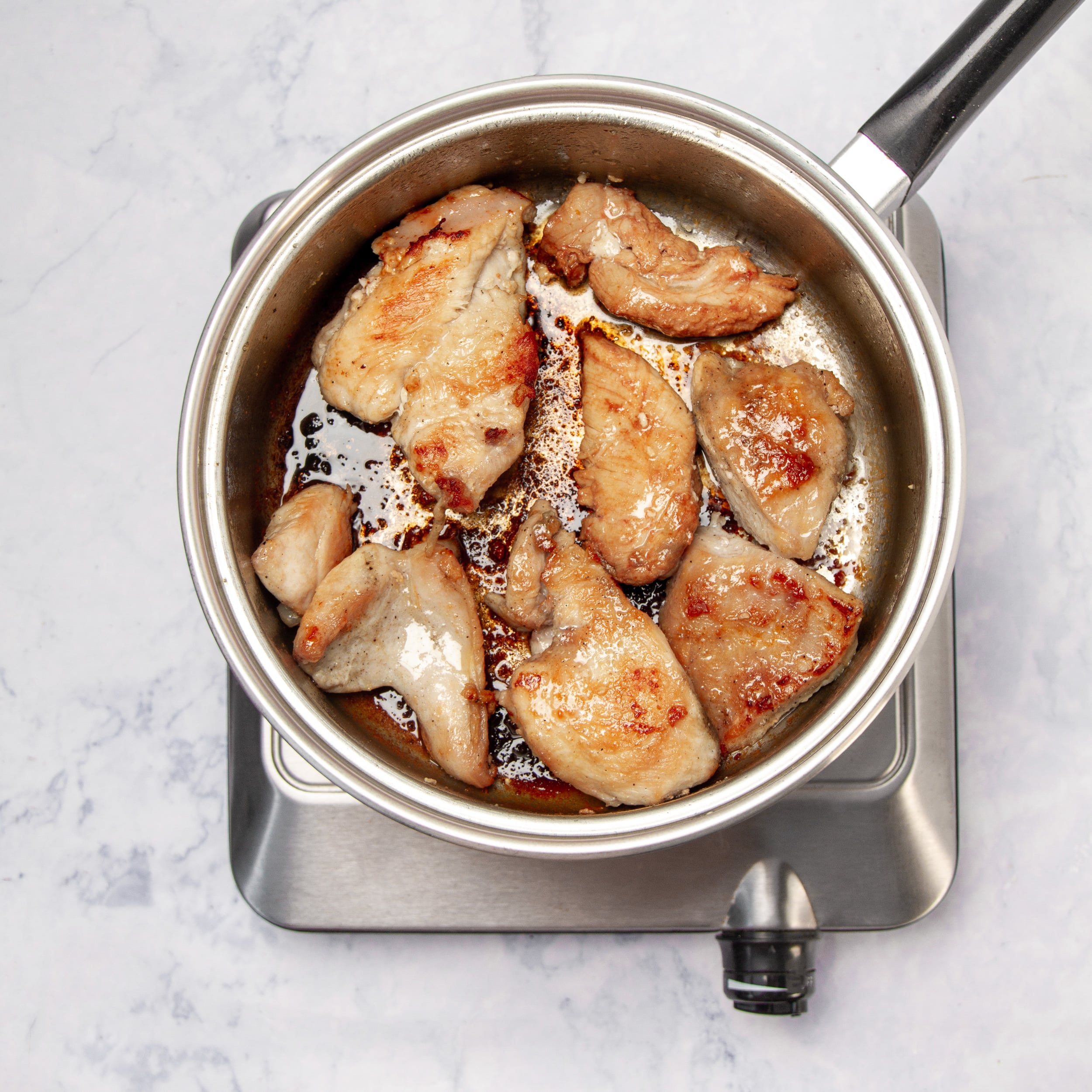 Seasoned chicken breasts browning in a skillet. 