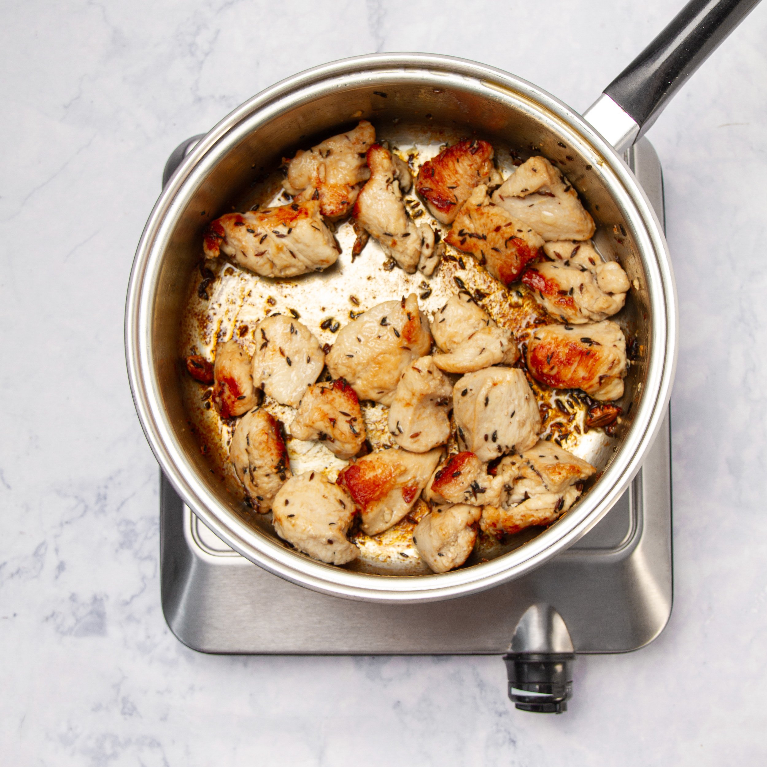 Chicken cooking with spices in a pan. 