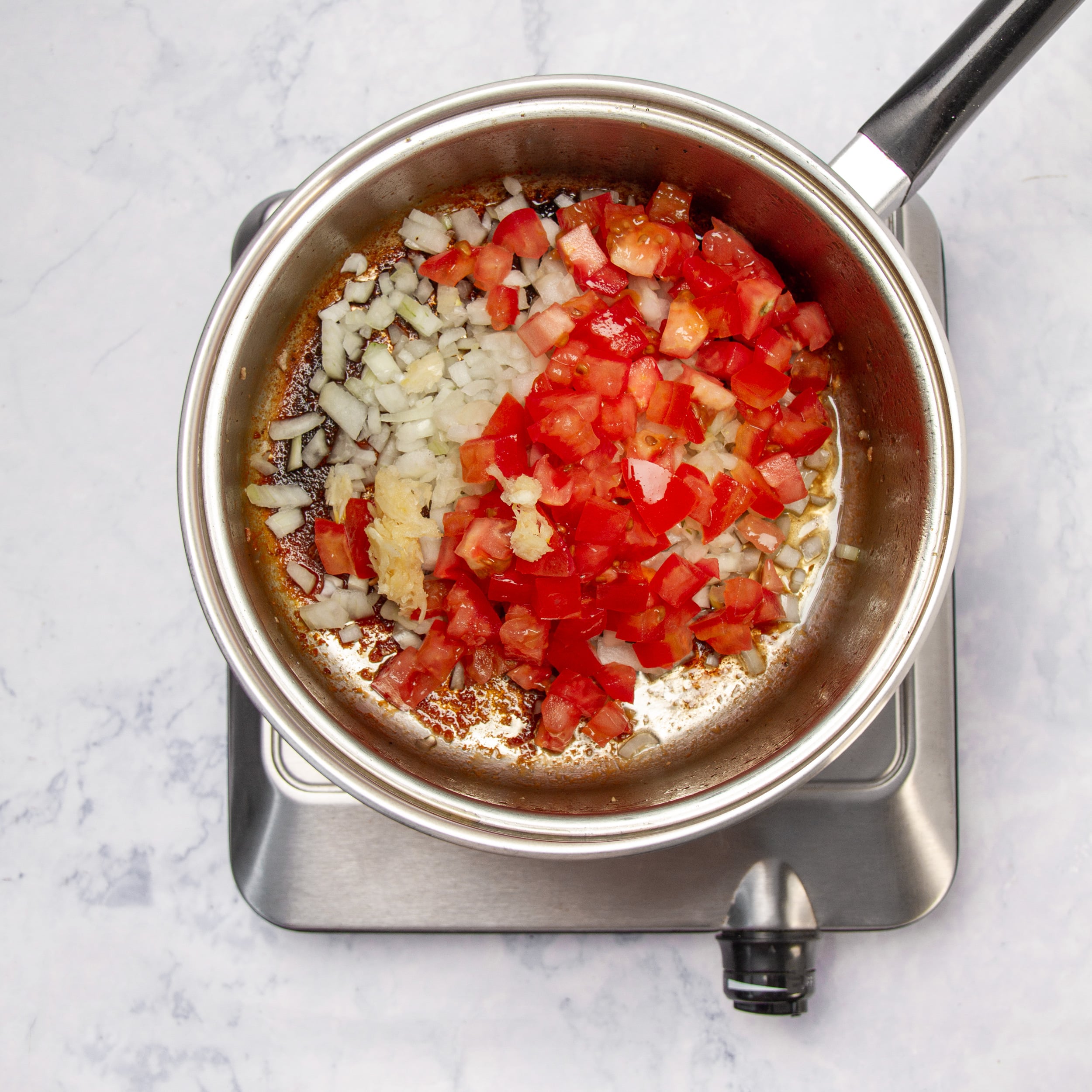 Tomatoes and onions saut&eacute;ing in a pan for the adobo sauce base. 
