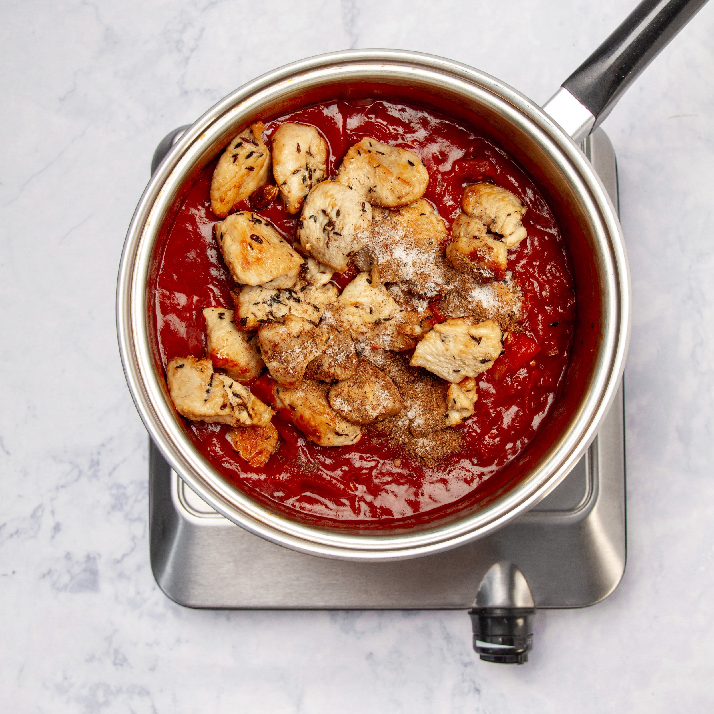 Chicken added to the pan of chili tomato sauce. 