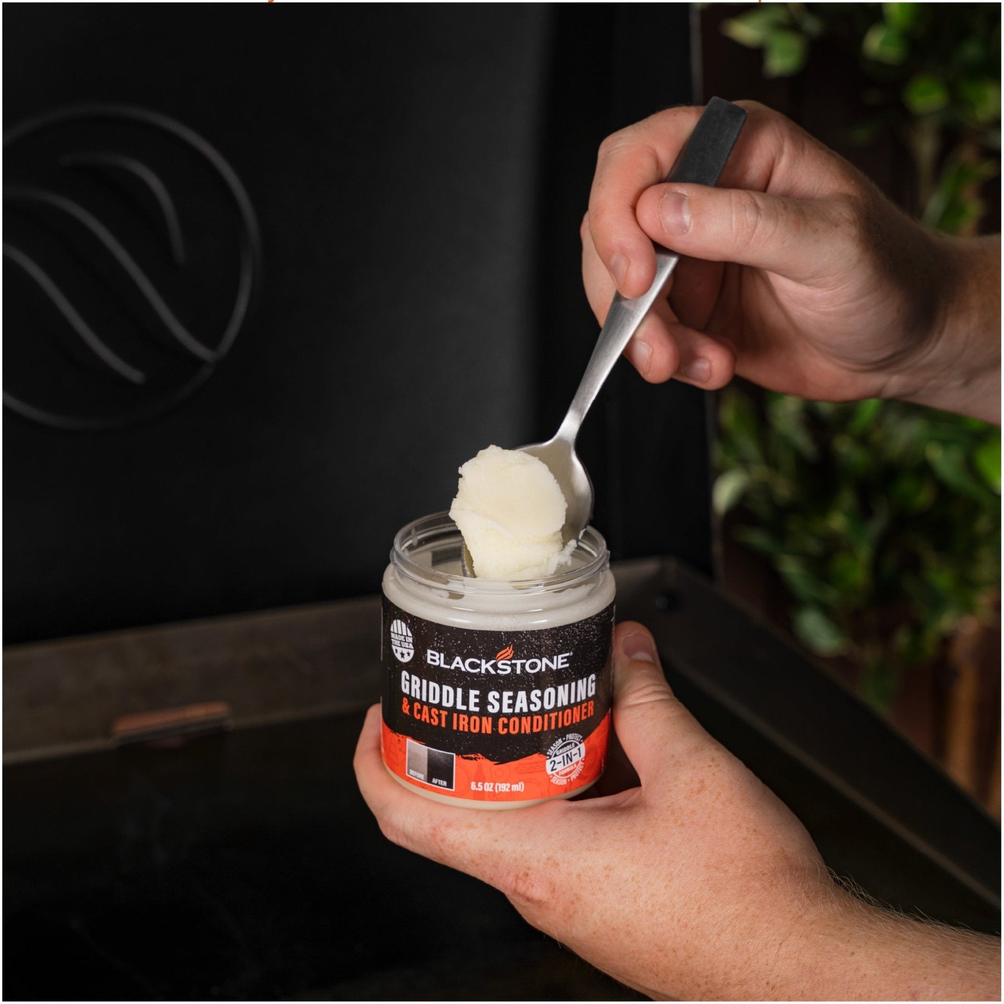 A hand scooping Blackstone Griddle Seasoning and Cast Iron Conditioner from the tub with a spoon