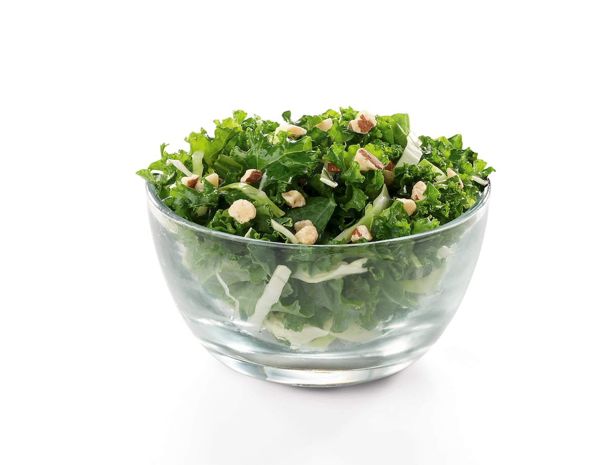 A Chick-fil-A Kale Crunch Side of curly kale and green cabbage topped with roasted almonds in a glass bowl
